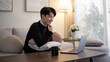 © wattana - Young man working on a laptop while sitting on a cozy sofa in a modern home living room.
