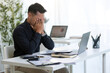 © wattana - Overworked entrepreneur managing tasks and feeling pressure while working on a laptop in an office.