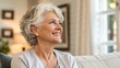 © engincan - Golden years. Head shot portrait beautiful happy senior adult lady retiree relax sitting on sofa at home looking aside with calm dreamy smile enjoy good health active retirement serenity of free time
