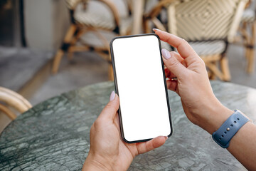 mockup woman's hand holding using smart phone with white blank screen pov at coffee shop, mobile app