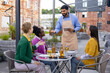 © sofiko14 - A waiter takes an order from three women seated at an outdoor restaurant table. They are enjoying drinks and conversation.