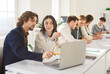 © Studio Romantic - Portrait of young college or university students group sitting in the classroom looking at the laptop monitor screen working on educational project together. Education and knowledge concept.
