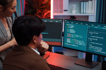 Smart IT developer looking at coding program application on computer screen of online website at back side, analyzing intelligent database system development on business marketing at office. Infobahn.