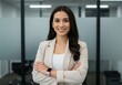 © shahida  - Confident young professional woman smiling with arms crossed in modern office setting