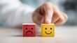 © Nimra - Hand chooses happy face block over sad face block representing positive attitude