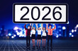 © Creativa Images - Diverse Business Team Lifting '2026' Sign Against City Lights