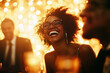 © Mediaphotos - Young Black woman laughing among group of people during festive celebration, wearing glasses, surrounded by blurred figures and sparkling golden lights in background