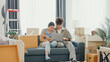 © tirachard - Young happy Asia couple sit on sofa couch use computer laptop online shopping furniture from decoration store in living room at home. Husband wife move new house, Apartment Rent And Ownership Concept.