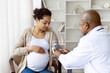 © Anastasiya - African American pregnant woman has blood pressure measured by doctor during prenatal checkup. Routine maternity care and health monitoring in clinic visit.