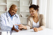 © Anastasiya - Female patient smiling while pointing at tablet screen held by cheerful doctor during a positive medical consultation at a clinic table, closeup shot