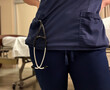 © Kelly - Nurse Standing at Bedside with Stethoscope in Scrub Pocket