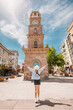 © EdNurg - Young woman with open arms enjoying the view of the historical Canakkale Clock Tower, Turkey, a popular travel destination