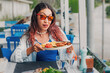 © EdNurg - Tourist enjoying traditional greek food in a restaurant by the sea, holding a plate of souvlaki and french fries