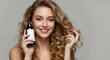 © RestuAry - Smiling woman with long blonde curls showcasing a hair care product.