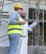 © Jack Tamrong - Arabic building project investor holding floor plan discussing with male contractor in construction site