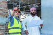 © Jack Tamrong - Arabic building project investor holding floor plan discussing with male contractor in construction site