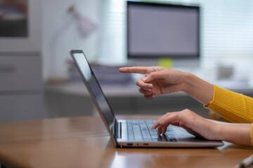 A woman is pointing at a laptop screen