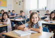 © Eliane - Happy elementary school student smiles at the camera while writing in her notebook, sitting at her desk in a bright and diverse classroom full of engaged children.