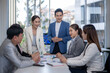 © Wasana - A group of people are sitting around a table in a conference room