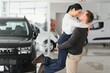 © Serhii - Beautiful young couple at car showroom exited because of buying a new car