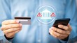 © Rezaul - Man holding credit card and smartphone with bank building icon and warning signs indicating financial risk or security alert