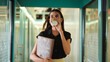 © Raushan_films - Indian happy young adult gen z woman lady take file paper hold cup in hand walk indoor office hall way place female staff expert girl agent drink coffee during break time going along work campus space
