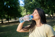 © Nenad - Close-up of beautiful fit woman drinking water outdoors, healthy lifestyle, refreshing moment during workout