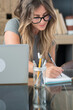 © simona - Professional young woman working in modern office with laptop and desktop computer – focused business environment, digital work, smart working and technology concept
