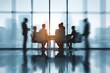 © Pavel - Businesspeople engage in discussion during an office meeting in a high-rise building with a city skyline view at sunset