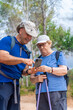 © MiguelAngel - Man with senior woman checking the phone enjoying a hiking day.