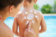 © Dmitriy K. - Mother applying sunscreen in sun shape on child's back near pool