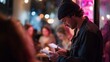 © fotofabrika - Young man writing notes in a trendy cafe during evening hours with blurred figures in the background