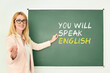 © New Africa - Teacher pointing at text You Will Speak English on green chalkboard. Language course