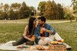 © La Famiglia - Couple enjoying romantic picnic and sharing juice in park
