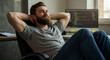 © Luiz - Man relaxing in office chair with hands behind head in front of computer looking upward smiling
