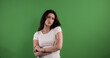 © 4kclips - Young woman is posing with crossed arms and a serious expression on green background