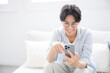 © kapinon - 部屋でスマホを見る、持つタップする眼鏡のハンサムな男性のクローズアップ