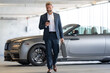 © Volodymyr - Business man outdoors. Rich business man enjoying success. Luxury businessman in elegant suit. Rich man front of expensive car. Luxury business travel. Confident rich business man in a classic suit.