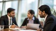 © N7 - Indian business executives engaged in confidential negotiation at boardroom table