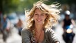 © Cheewynn - A smiling woman with windblown hair enjoys a sunny day outdoors, with blurred cyclists and greenery in the background