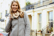 © fStop - Portrait of smiling blond woman in warm jacket standing in street