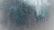 © Prasong Takham - Closeup view of rain droplets on a glass window reflecting the moody and atmospheric blue and gray tones of a stormy sky  The wet surface creates a textured abstract and contemplative background