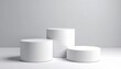 © Dewi - Three White Cylindrical Podiums on Light Gray Background
