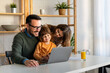 © NDABCREATIVITY - Happy family with kids having fun using laptop together, parent and children relaxing at home