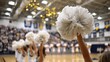 © Quail 8s Studio - Close up of a cheerleader's white pom pom held up in a gymnasium with blurred spectators in the background