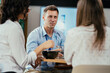 © Suteren Studio - Young businessman eating healthy salad lunch with colleagues in modern office cafeteria