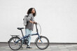 © kite_rin - Young beautiful woman with bike over white wall background in a city, Full length portrait of smiling student girl with bicycle outdoor, Modern healthy lifestyle, travel, casual business concept