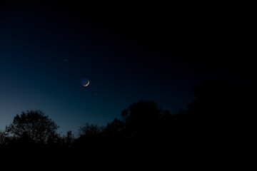 Wall Mural - crescent young moon with stars, planets and countryside silhouettes.