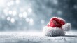 © Nikolai - Small red Santa hat resting on fresh white snow with soft natural daylight, winter holiday concept.