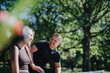 © qunica.com - A cheerful couple laughing and interacting in a lush green park with sunlight streaming through the trees. The lively atmosphere and natural beauty convey feelings of connection, joy, and relaxation.
